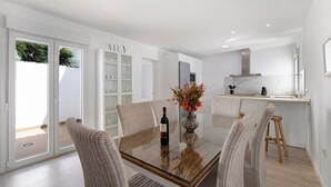 Une cuisine moderne avec des meubles blancs, un réfrigérateur en acier inoxydable et un plan de travail en bois.