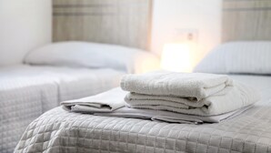 Une chambre d’hôtel avec deux lits, chacun doté d’une tête de lit, d’une pile de serviettes blanches pliées et d’une couvre-lit matelassée.