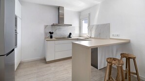 Une cuisine moderne dotée d’un four encastré, d’une hotte en acier inoxydable, d’un pare-feu en marbre et de tabourets en bois.