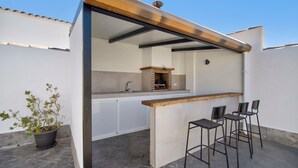 Un espace cuisine extérieur avec un bar, des tabourets et une plante en pot.