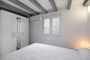 Une chambre à coucher comprenant un lit, une armoire, une fenêtre et un appareil de climatisation.
