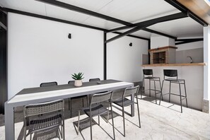 Un espace de restauration extérieur moderne, avec une table et des chaises, une plante en pot et un four en briques.