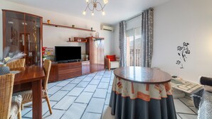 Un salon avec un téléviseur, des meubles en bois, une table ronde et un mur décoratif.