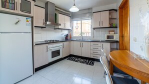 Une cuisine équipée d’un réfrigérateur, d’une cuisinière, d’un four à micro-ondes et de meubles de rangement en bois.