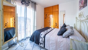 Une chambre à coucher avec un lit, un miroir, une armoire et une fenêtre avec des rideaux.