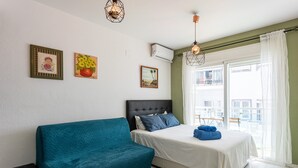 A bedroom with a bed, a blue sofa, and a window with a view.