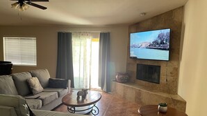 Un salon comprenant un canapé, une table basse, un téléviseur fixé au mur et une cheminée.