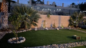 Un jardin aménagé avec des palmiers, une bordure de pierres et un chemin pavé.