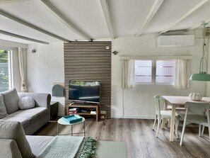 Ein modernes Wohnzimmer mit einer Couch, Fernseher, Esstisch und Stühlen.