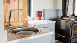 A kitchen with a sink, wooden cabinets, a stove, and a box of Tomatin wine. - Our off-grid Boathouse with hot tub sleeps 2 with amazing lochside views. (Tomich)