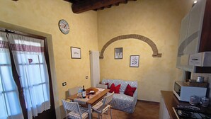 A compact kitchen with a dining table, chairs, a sofa, and a stove.