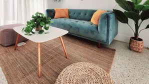 A living room with a teal sofa, a white coffee table, and a large green plant. - Cozy Apartment Near Brickell IV (Miami)