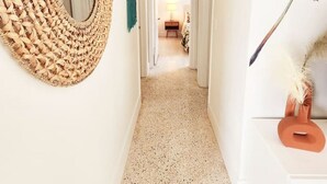 A hallway with a woven wall mirror, a teal towel, and a palm plant. - Cozy Apartment Near Brickell IV (Miami)