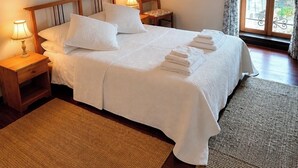 Un lit bien fait, avec du linge de lit blanc, une tête de lit en bois et une table de chevet avec une lampe.