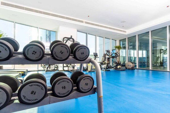 A gym with weightlifting equipment, exercise machines, and a blue floor.
