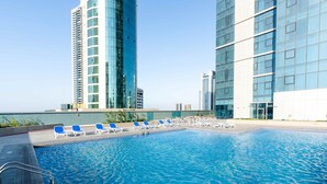 A rooftop pool with lounge chairs and high-rise buildings in the background. - S Plaza Suites Hotel (Manama)