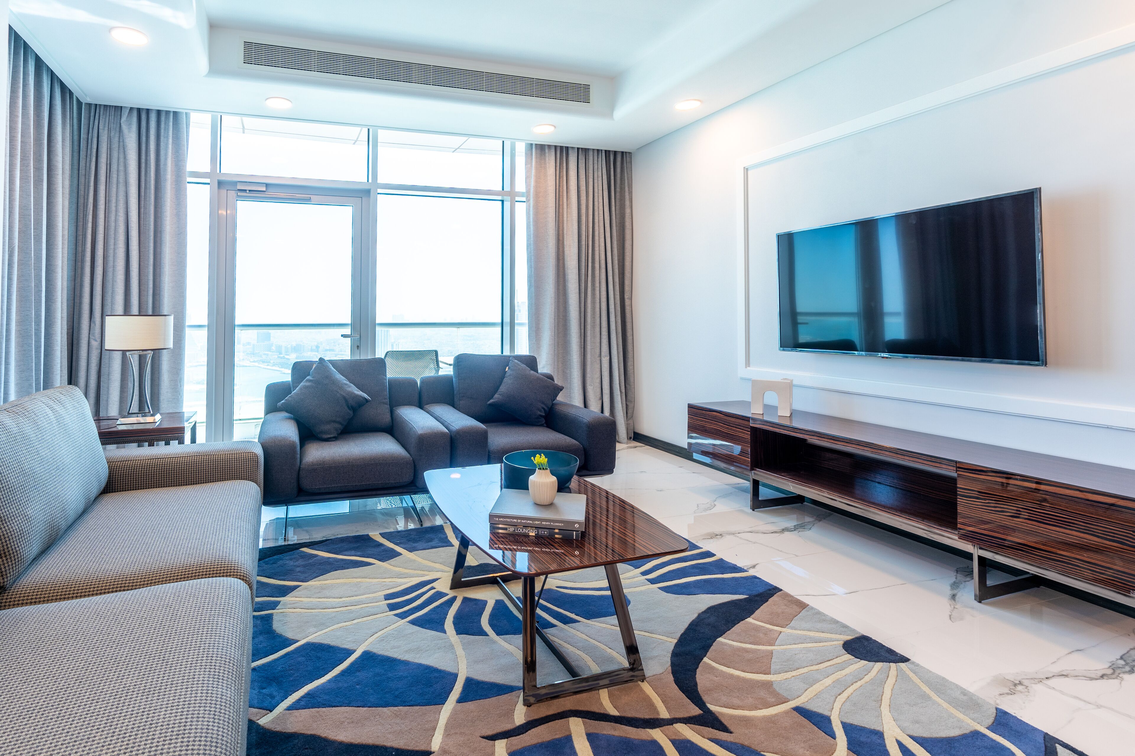 A modern living room with a sofa, a coffee table, and a flat-screen TV mounted on the wall.