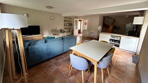 Um espaço compacto com sofá, mesa de jantar com cadeiras, televisão e cozinha equipada com micro-ondas.