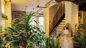 A modern interior with a staircase, indoor plants, and a ceiling fan. - Atelier Hotel (Siem Reap)