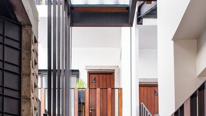 A modern architectural design with a glass floor leading to a lower level, surrounded by wooden and metal railings. - Atelier Hotel (Siem Reap)