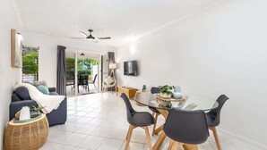 A modern living room with a sofa, dining table, chairs, and a TV.