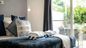 A bed with a dark blue headboard, a white and blue patterned pillow, and a white towel.