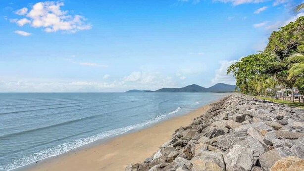 A beach with a rocky shoreline, calm sea, and distant mountains. - Seaside Serenity—Family Escape with Private Spa (Machans Beach)