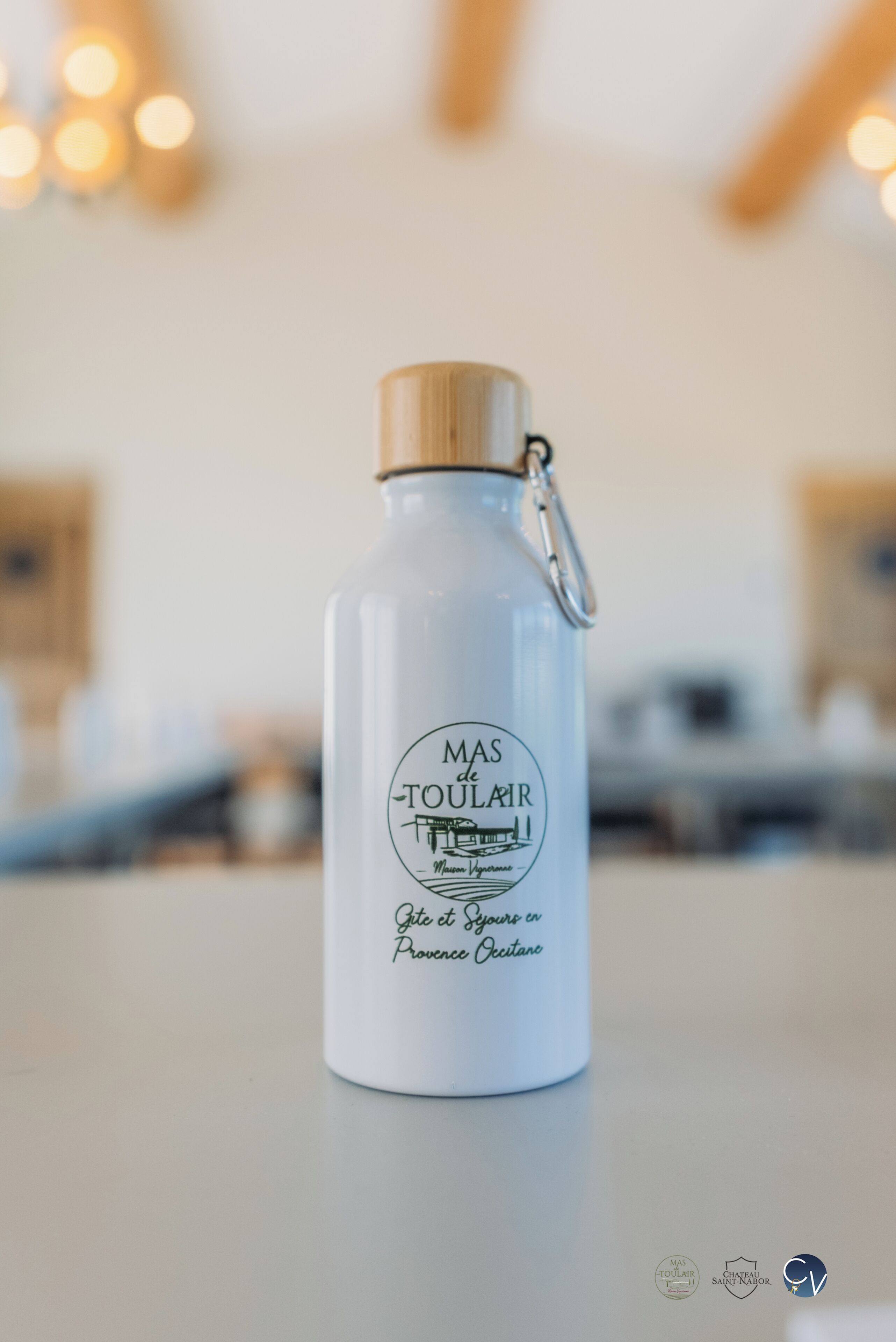 A white water bottle with a wooden cap and a metal clasp, labeled "MAS de Toulair."