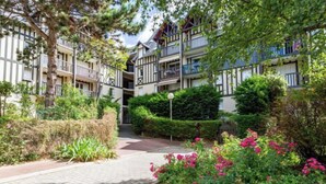 A courtyard with a paved walkway, surrounded by lush greenery and flowering plants. - Le Clos Mathilde by Interhome (Cabourg)
