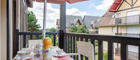 A balcony with a table set for tea, a bottle of juice, and a teapot.