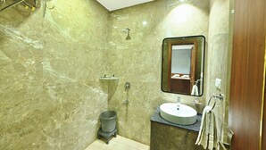 A bathroom with a marble wall, a sink, a mirror, and a shower. - Hotel Sagar residency (Bikaner)