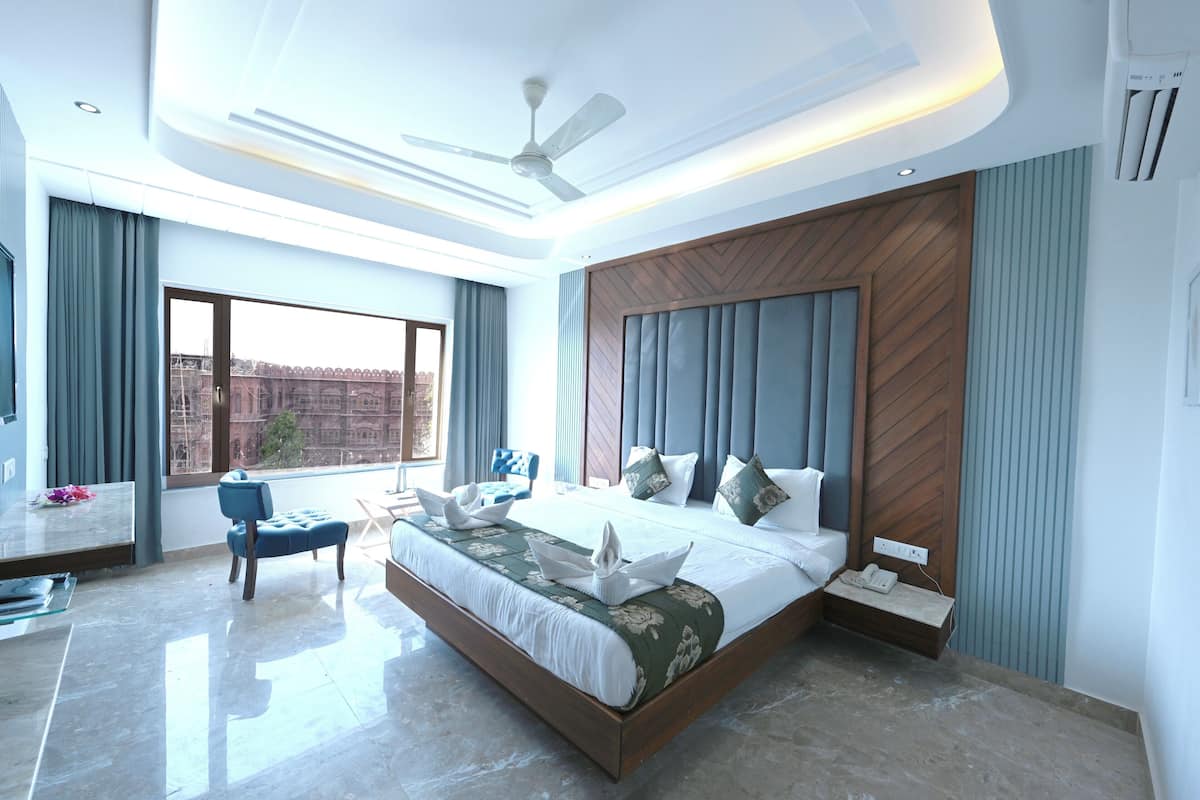 A modern bedroom with a large bed, a ceiling fan, and a view of a building outside.
