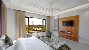 A hotel room with a large bed, a TV mounted on the wall, and a view of the outdoors. - Hotel Sagar residency (Bikaner)