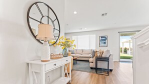 A modern living room with a white console table, a beige sofa, and a black-framed coffee table. - Rockslide House - New build, resort style pool, endless amenities (3 miles to festivals) (Coachella)