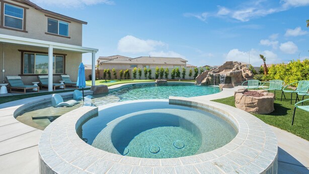 A backyard with a hot tub, a swimming pool, and a waterfall feature. - Rockslide House - New build, resort style pool, endless amenities (3 miles to festivals) (Coachella)