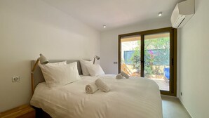 Un lit bien fait, avec du linge de lit blanc et des oreillers, une lampe de chevet et une serviette enroulée posée sur le lit.