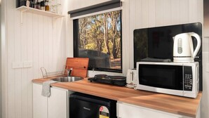Una cocina compacta con encimera de madera, un lavabo, un microondas, un tostador y un hervidor.