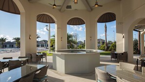 An outdoor patio area with tables and chairs, a central island, and views of a street and palm trees.