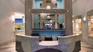 A reception area with a marble counter, wooden ceiling beams, and hanging spherical light fixtures.