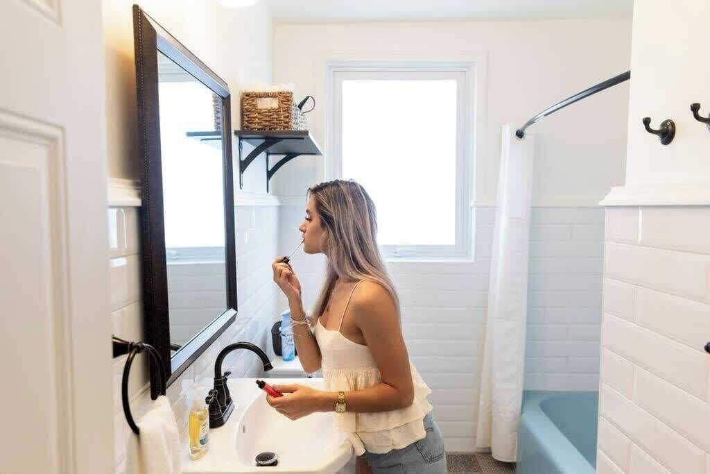 A bathroom with a white sink, a mirror, and a window.