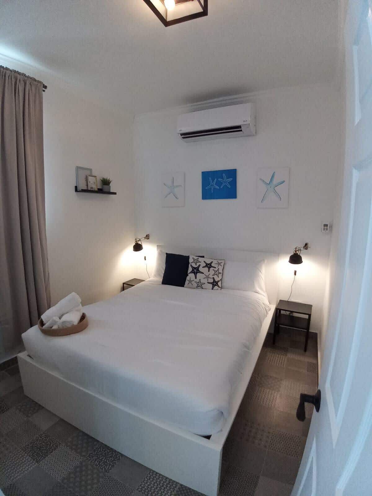 A neatly made bed with a pillow and a small bedside table with a lamp.