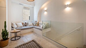 Ein modernes Interieur mit Glastrennwand, gepolsterten Sitzgelegenheiten, einem Topf mit einem Kaktus und einer gewebten Leuchte.