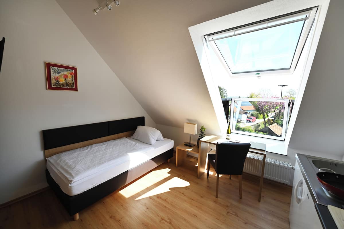 Un dormitorio con cama, escritorio y silla. Cuenta con un tragaluz y un radiador.