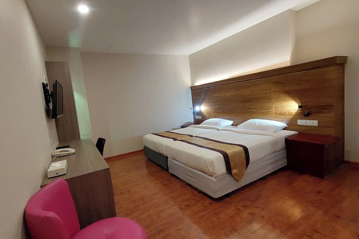 A hotel room with a large bed, a desk with a chair, and a wooden headboard.