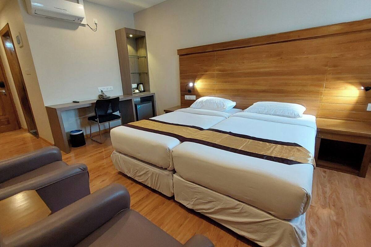 A hotel room with a large bed, a desk, a chair, and a wooden headboard.