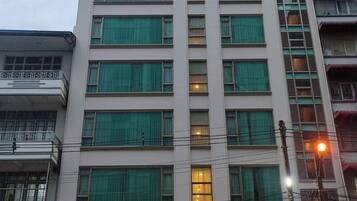 Un hotel de varios pisos con fachada moderna, amplias ventanas y un llamativo letrero de neón que dice "HOTEL GRAND GALAXY".