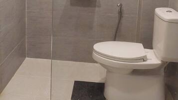 Een moderne badkamer met douche, toilet en betegelde vloer.