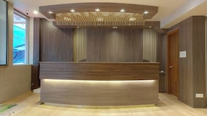 A reception desk with a modern design, featuring a wooden finish and integrated lighting. - Hotel Grand Galaxy (Yangon)