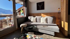 A cozy room with a bed, a small table, and a view of a snowy mountain.