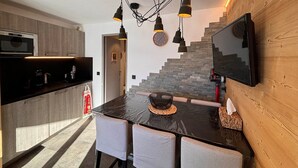 A modern kitchen with a black countertop, a built-in microwave, and a wooden wall with a TV mounted on it.